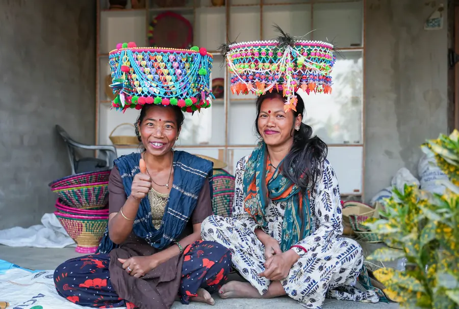 Two Tharu makers in beaded headdresses they have woven, among their baskets